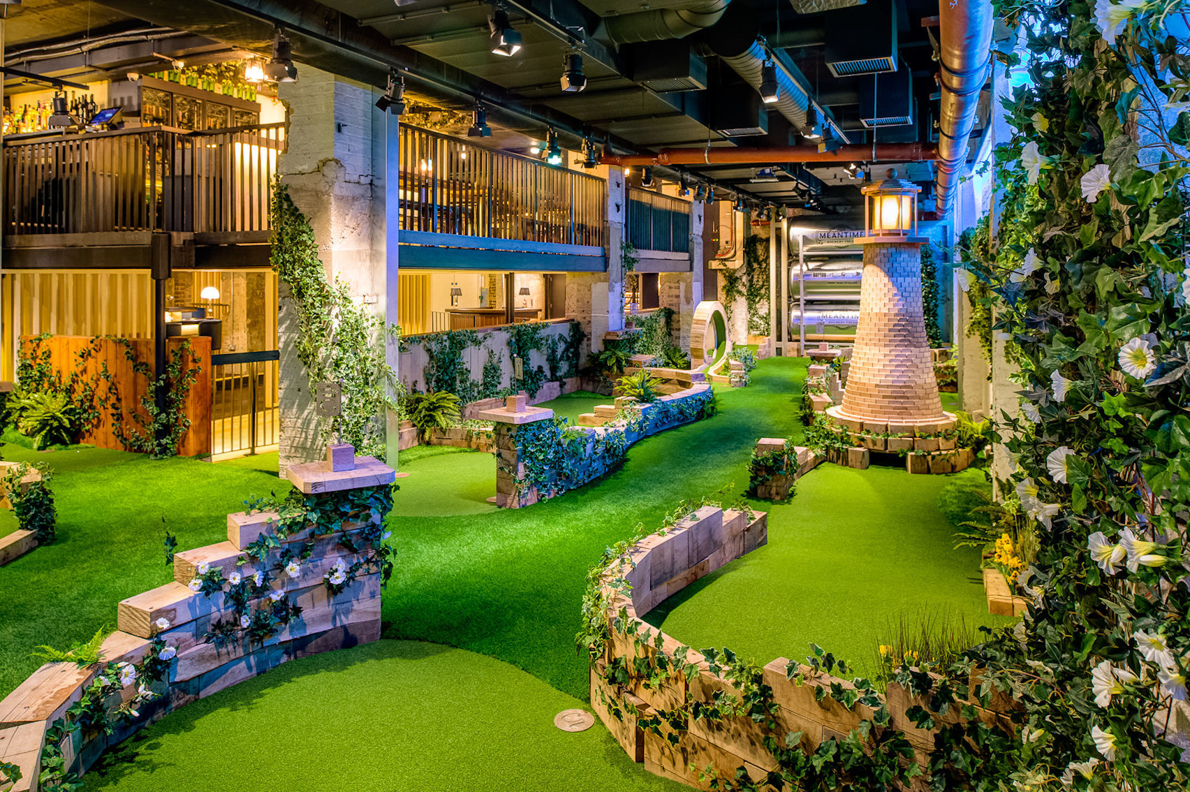 Indoor crazy golf course with bar area lit by bright yellow lighting